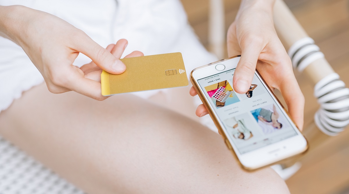 woman holding credit card next to phone