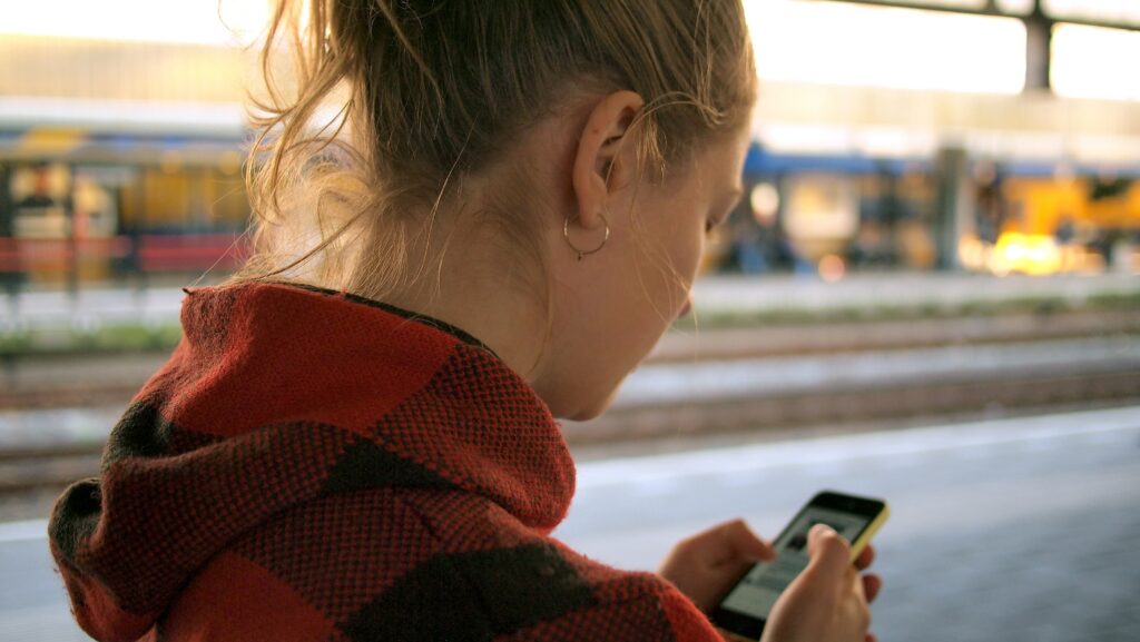 Women at train station using a mobile phone