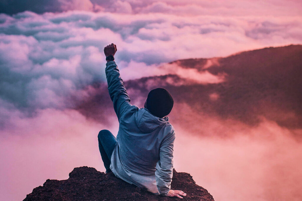 Person at the top of mountain with fist in the air