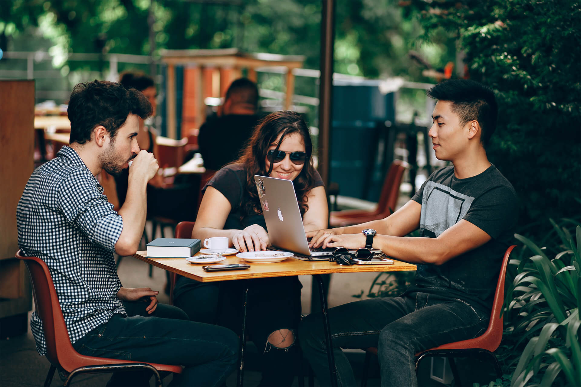 Three young adults sitting around table socialising